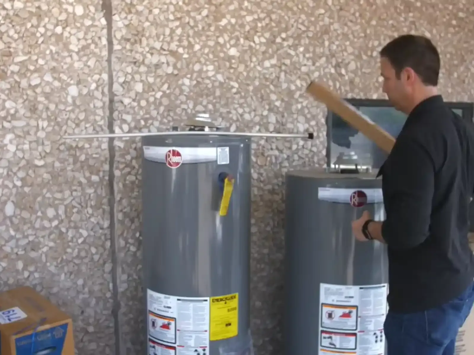 Technician beside two tank water heaters on a garage floor